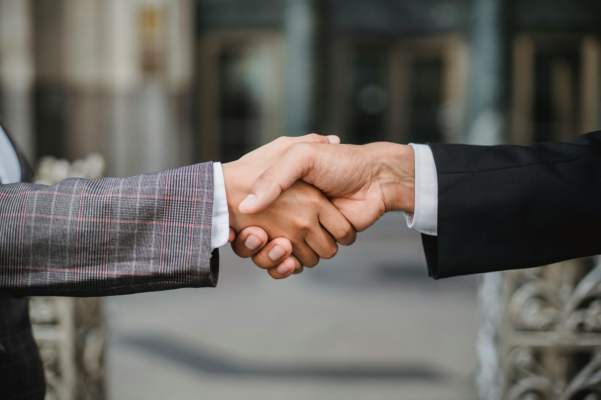 Close-up of two people in business attire shaking hands, symbolizing agreement or partnership.