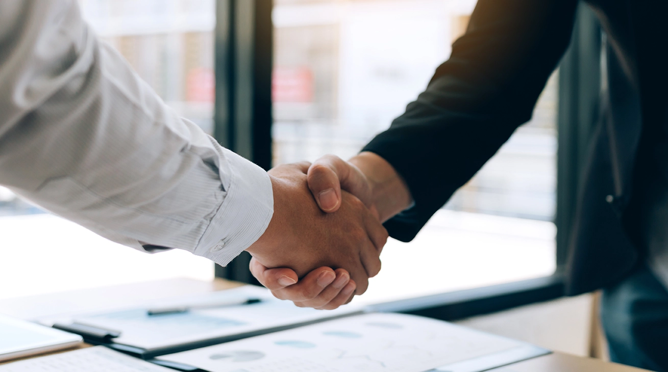 Two professionals shaking hands in an office setting.